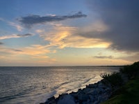 a stormy sky over the ocean and a rocky shore